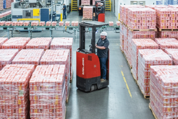 Warehouse worker operating a forklift among stacked pallets of packaged food products, illustrating efficient logistics in food manufacturing and distribution.