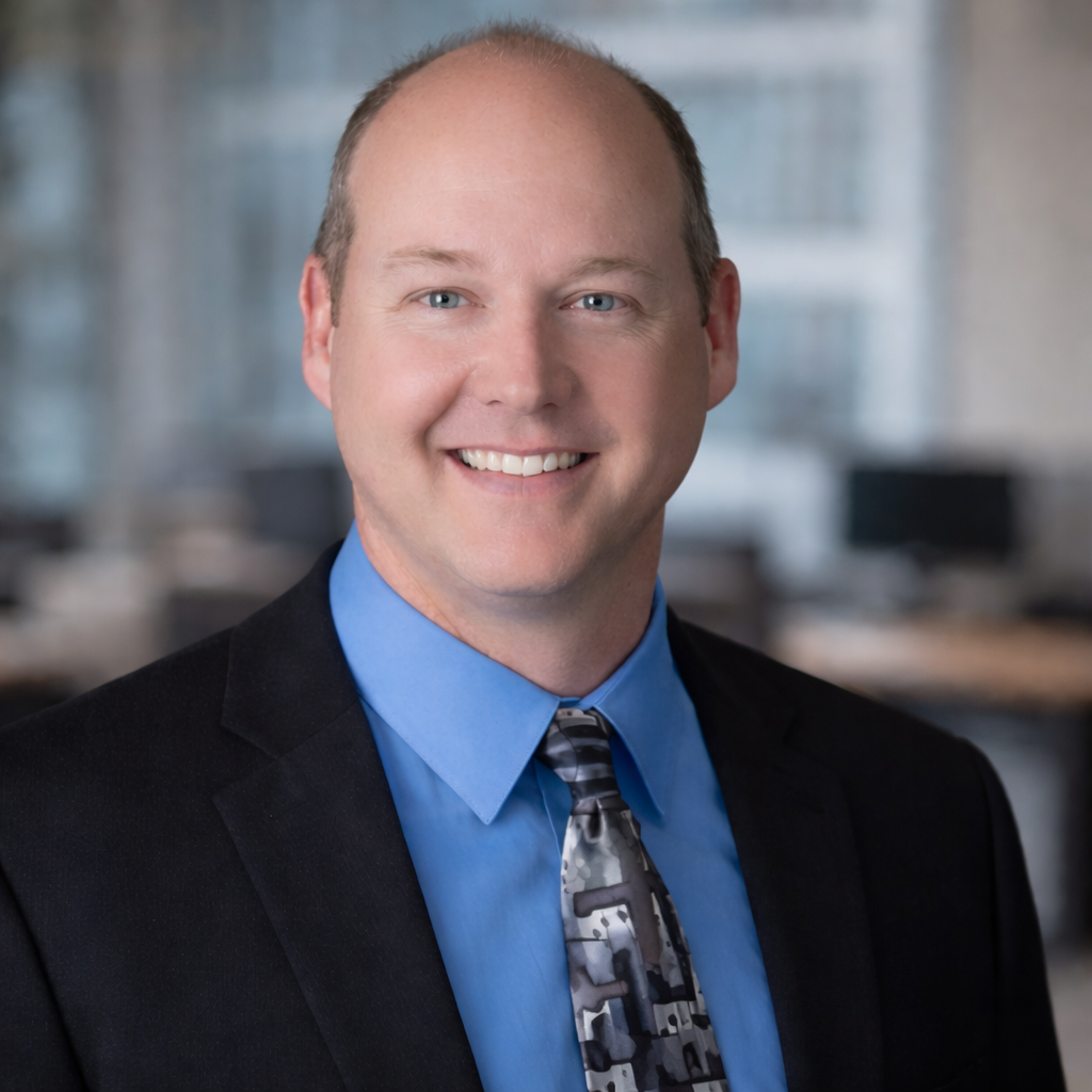 Keith Barr, Director of Business Strategy at Firefly Business Group, smiling in a professional setting with a blue dress shirt and patterned tie, emphasizing leadership in ERP solutions for food industry.